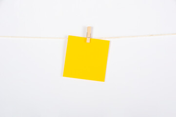 Postik naranja colgado con pinza sobre fondo blanco para concepto ejercicio, recordatorio o mensaje.