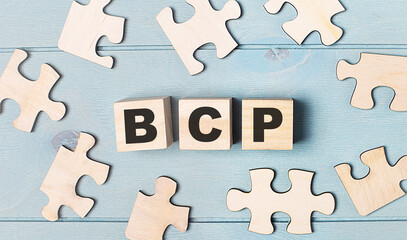 Obraz premium Blank puzzles and wooden cubes with the text BCP Business Continuity Plan lie on a light blue background.