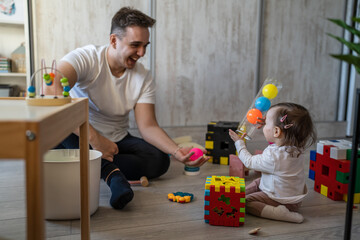baby girl and her father young caucasian man with daughter playing at home happy sitting on the...