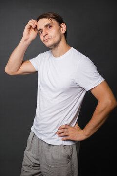 A handsome young man in a white t-shirt stands on a gray background. mockup