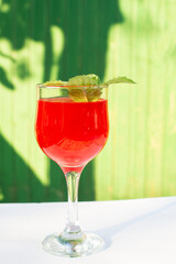 a glass with red juice on a green background in summer