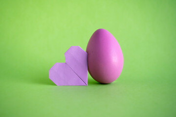 Easter egg and origami heart on green backgorund.