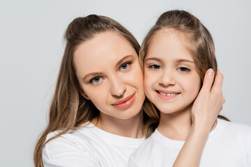 woman hugging happy daughter and looking at camera isolated on grey.