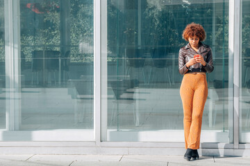 afro american girl standing with mobile phone on the street