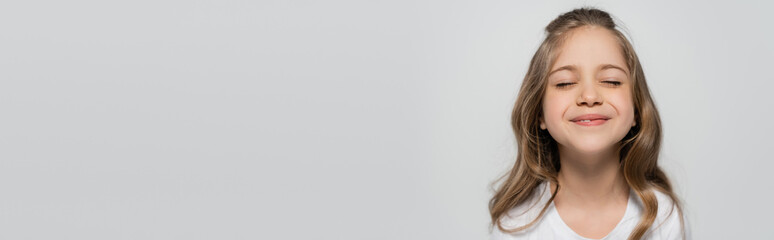 Fototapeta premium portrait of joyful girl with closed eyes isolated on grey, banner.