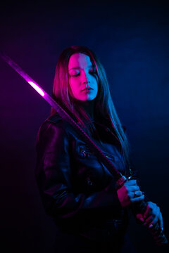 Cyber girl in a black leather jacket at dusk holds a katana. A woman in a club with a colored pink-blue light holds an Asian sword.