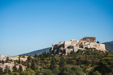 Fototapeta na wymiar View of the ancient Athenian Acropolis on a hill with trees, Athens, Greece.