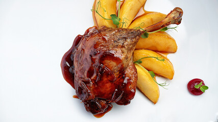 Duck leg with pear in caramel, on a white plate