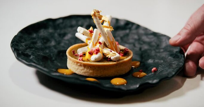 Chef finishing and serving gourmet dessert in fine dining restaurant. Close up on dish and hands