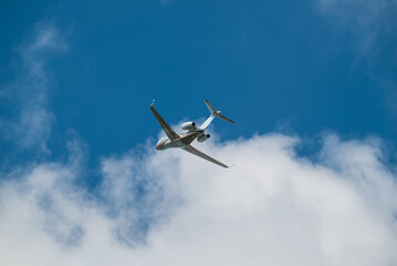 Fototapeta na wymiar Airplane Jet flying overhead against blue sky and white clouds