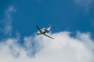 Airplane Jet flying overhead against blue sky and white clouds