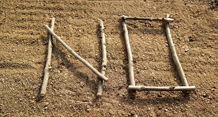 Word NO from small wooden sticks. Capital letter on sandy background. Wooden alphabet.