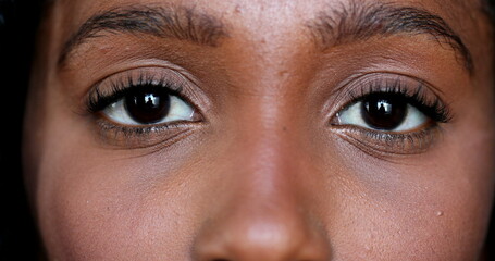 Close-up African young woman eyes looking at camera, Macro closeup black girl eye - Powered by Adobe