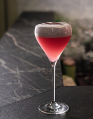 Red cocktail with air foam on the table in the bar