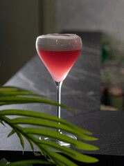 Red cocktail with air foam on the table in the bar