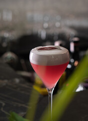 Red cocktail with air foam on the table in the bar