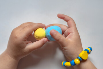 A child make the flag of Ukraine dough. Child with plasticine in the colors of the flag of Ukraine in hands. Children's creativity. DIY holiday handicraft and craft tools. Pray for Ukraine.