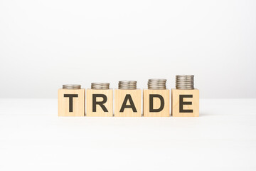 Trade text written on wooden block with stacked coins on white background