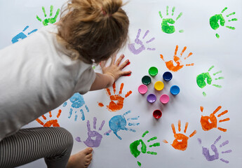 Handprint and footprint imprint by child in diffrent colors on white paper. Fun, education and sensory play. Stay at home with childen. Creativity and art