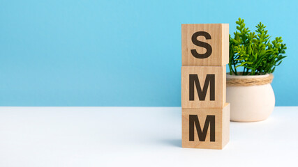 smm - word from wooden blocks with letters, blue background. copy space available