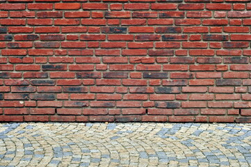 Industrial background, empty grunge urban street with old vintage brick wall and granite cobblestone pavement.