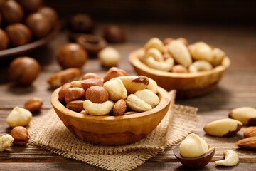 Various nuts in bowl - cashew, hazelnuts, almonds, brazilian nuts and macadamia on a wooden table. Healthy vegetarian food.