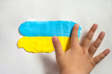 A child make the flag of Ukraine dough. Child with plasticine in the colors of the flag of Ukraine in hands. Children's creativity. DIY holiday handicraft and craft tools. Pray for Ukraine.
