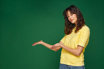 Beautiful young girl presenting advertising space on palms pointing to copy space, holding empty place for advertisement