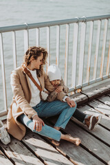 portrait of mom and daughter sitting on a wooden bridge on a sunny day