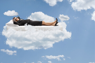 Businesswoman floating on a mattress up in the sky
