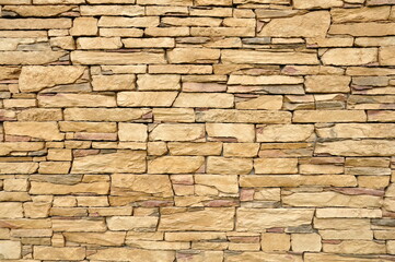 Part of the beige stone wall. Brown rock wall background texture.