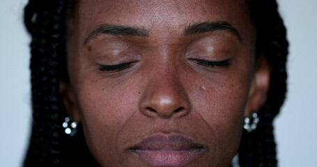 African woman closes eyes in meditation, close-up portrait face closing eye in contemplation