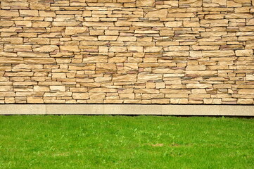 Part of the stone wall. Brown brick wall background texture. Stone wall with grass. Grass with brown brick wall background texture.