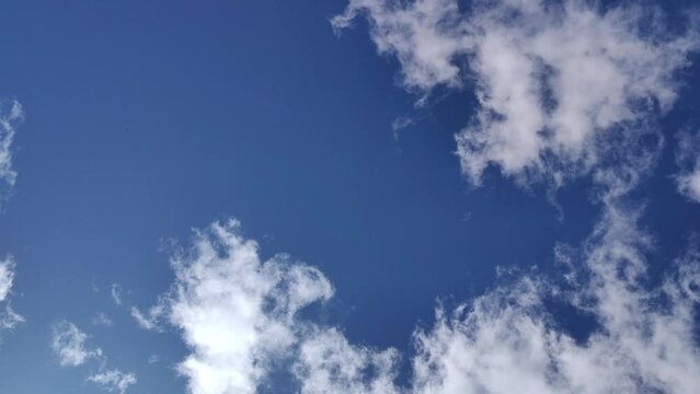 Timelapse em &acirc;ngulo baixo do sol no c&eacute;u azul de ver&atilde;o, com nuvens brancas em movimento e raios de sol iluminando a paisagem ensolarada. Longa dura&ccedil;&atilde;o 4K 30fps