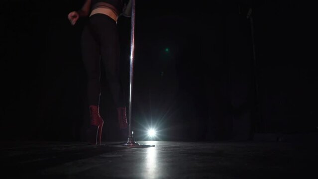 Pole dance in studio at black background. Striptease night club.