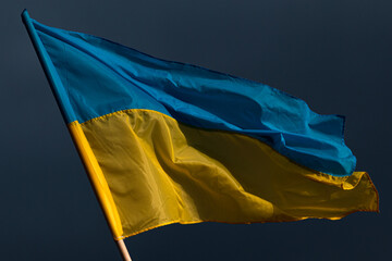 Ukraine flag waving with black dramatic sky behind.