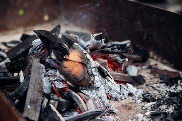 A brightly burning bonfire with a red flame made from wood in an outdoor grill.An adventurous lifestyle in travel. Active weekend recreation in the wild outdoors.