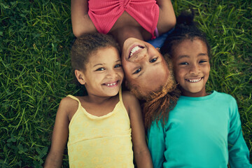 Fresh air and fun. High angle portrait of three little girls lying on the grass together outside.