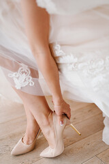 The bride puts on wedding shoes on her tender feet. Close up.