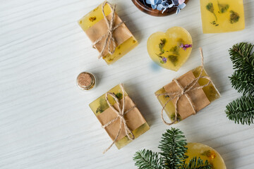 Fototapeta premium Top view of handmade soap bars near flowers and pine branches on table.