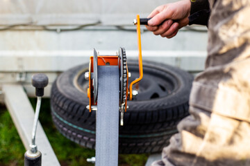 A man spins the winch handle on a car trailer. Towing and transportation of special equipment, loading and unloading of cargo