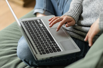 Young beautiful smiling woman using laptop lying on the couch. Concept of freelance job, home office. Female using technology for learning, shopping, e-commerce, communication, social media