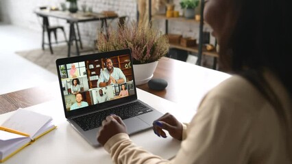 Young African-American woman using laptop computer for video connection with diverse group of people, female involved video conference with multiracial team, a lot of colleagues profiles on display