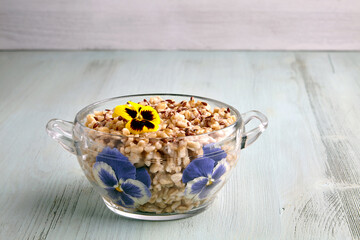 Whole grain oat flakes with flax seeds in a glass bowl decorated with flowers