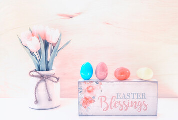Easter background with wooden plaque with the inscription in English "Easter Blessing". Bright colored eggs are a symbol of Easter and delicate tulips. Vintage style