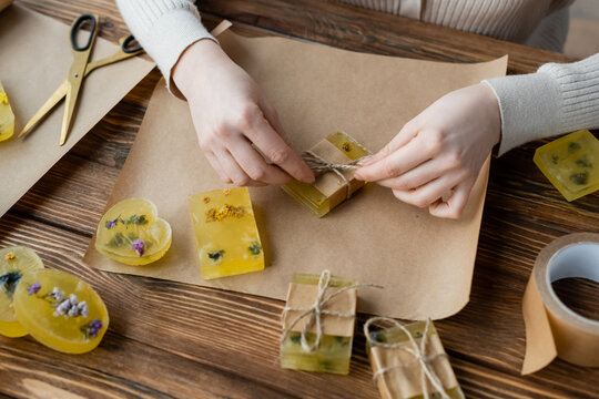 craftswoman packaging handmade soap on craft paper on table.