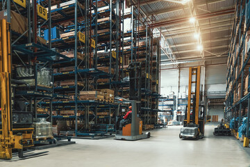 Warehouse of logistic company with forklifts. Large distribution storehouse with high shelves.