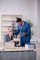 Old male boss and young male employee working in the office