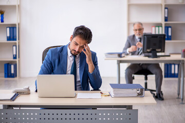 Old male boss and young male employee working in the office