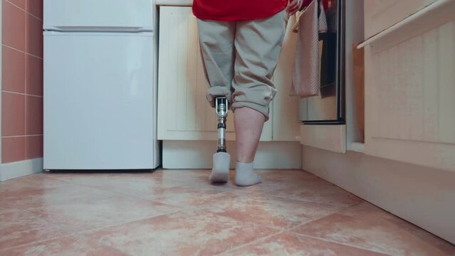 Long cinematic shot, beautiful happy disabled woman with bionic cyber prosthetic leg walks in kitchen to enjoy coffee.